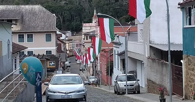 Rua de paralelepípedos no centro de Santa Teresa - ES com bandeiras da Itália nos postes e a igreja matriz ao fundo