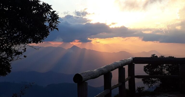 Serra do Caparaó ao pôr do sol vista da área de acampamento Tronqueira, com guarda-corpo de madeira em primeiro plano