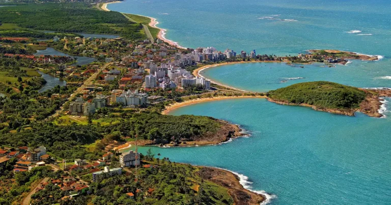 Vista aérea da Enseada Azul em Guarapari, com as enseadas de água azul-turquesa, as faixas de areia curvas e os costões verdes de Nova Guarapari