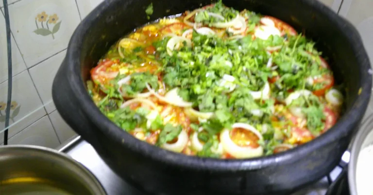 Moqueca capixaba de peixe na panela de barro, coberta pelas camadas de rodelas de tomate, cebola e coentro picado