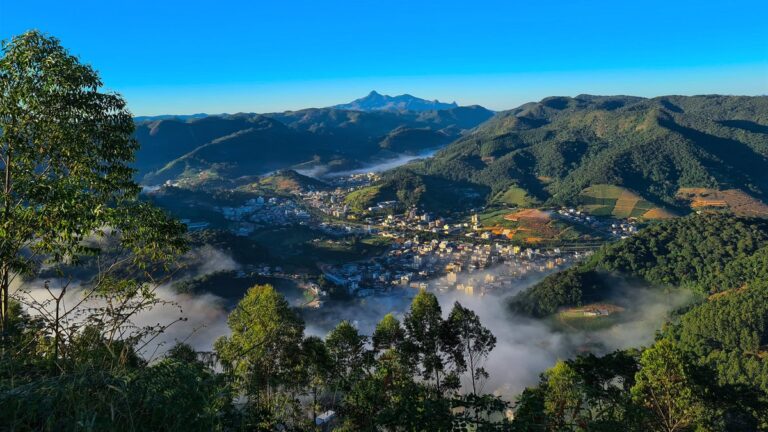 Vista da cidade de Venda Nova do Imigrante (ES) no vale, com neblina, mata e montanhas em volta