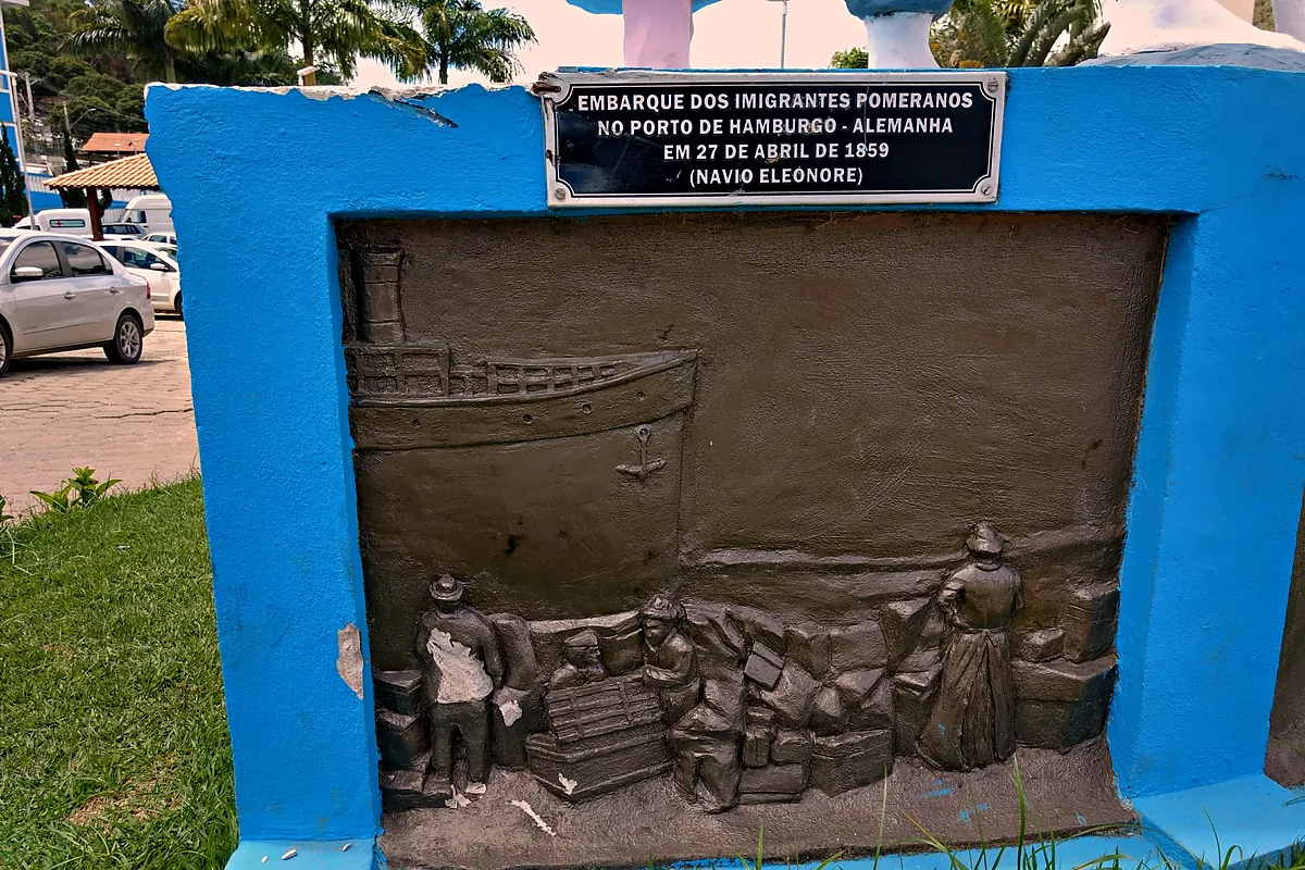 Painel em relevo do monumento da imigração pomerana mostrando o embarque dos imigrantes no porto de Hamburgo, com a placa de 27 de abril de 1859 e o navio Eleonore