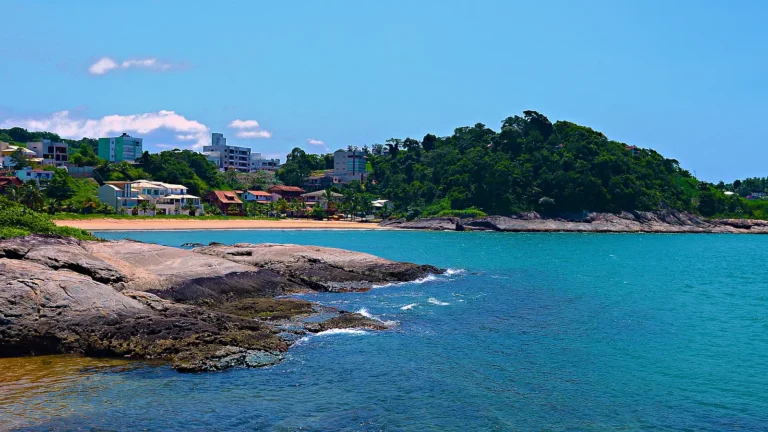 Praia dos Namorados, em Iriri, Anchieta (ES), com mar azul e costão de pedra em dia de sol