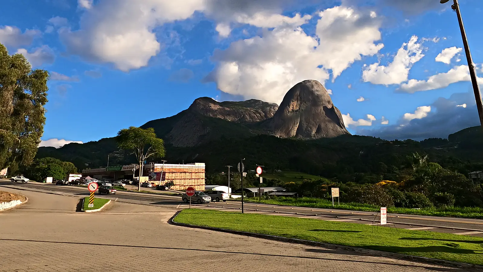 A Pedra Azul vista da BR-262, na vila de Pedra Azul, em Domingos Martins (ES), com o trevo da rodovia e o comércio em primeiro plano