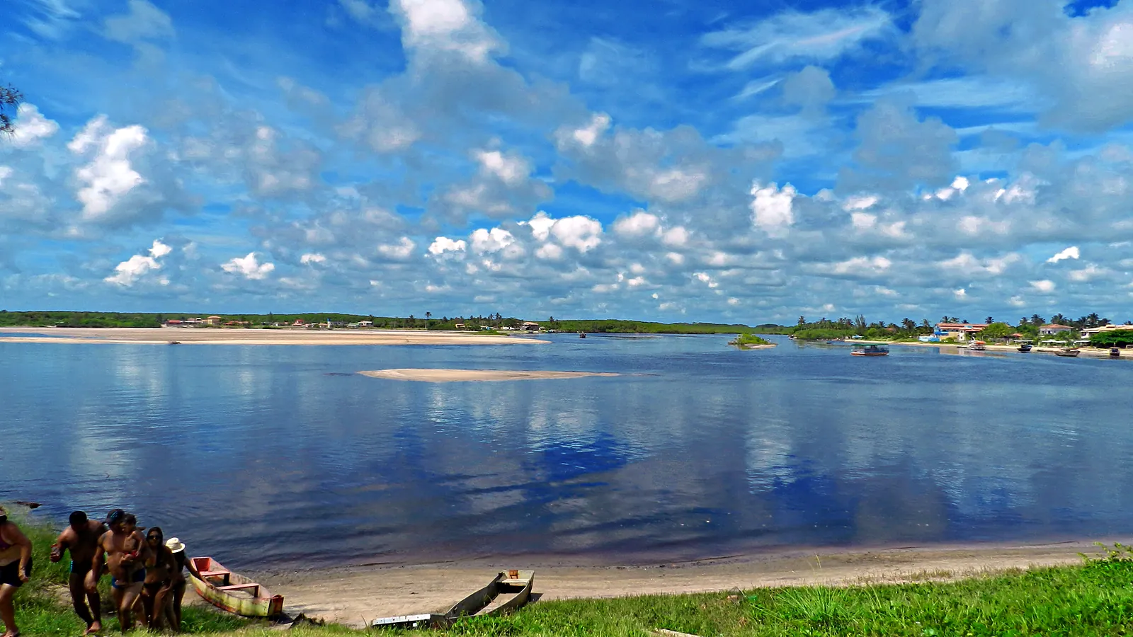 Rio Mariricu em Barra Nova, perto da foz, com canoas na margem em Barra Nova, na ponta sul da Ilha de Guriri, com canoas na margem e céu azul