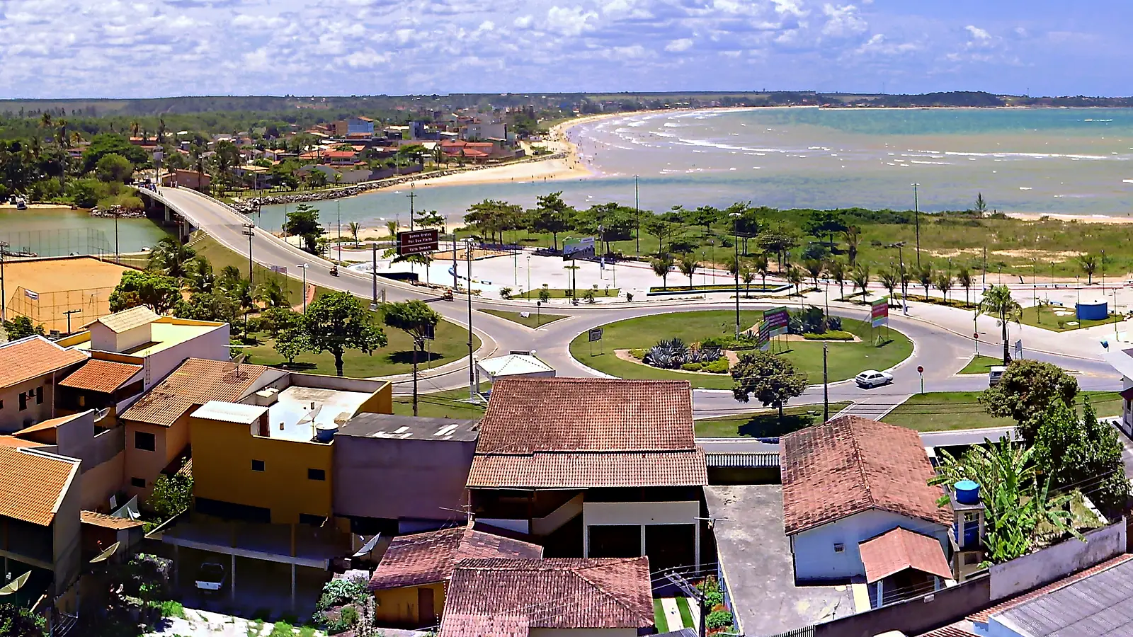 Ponte da ES-010 sobre a foz do Rio Reis Magos vista do alto de Nova Almeida, na Serra (ES), em 2009, com a rotatória em primeiro plano e a curva de areia da Praia Grande, em Fundão, ao fundo